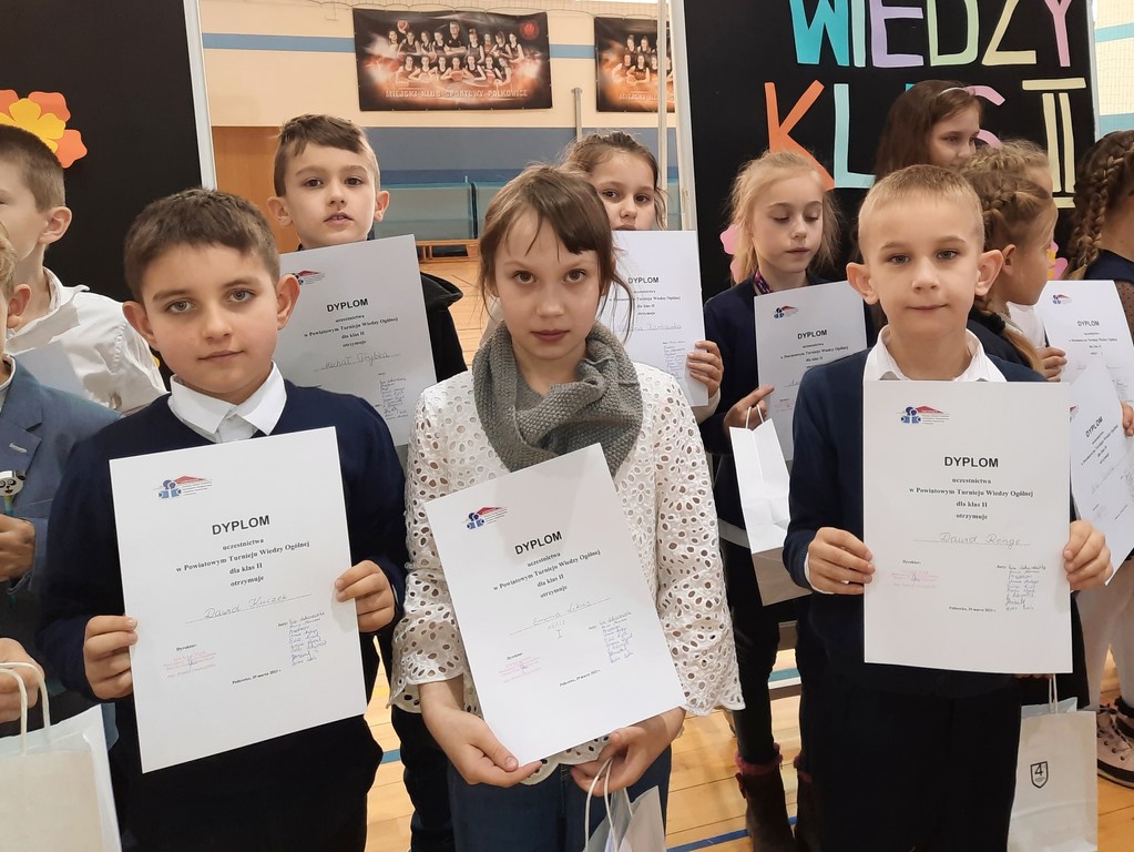 Uczniowie pozują do pamiątkowego zdjęcia z dyplomami