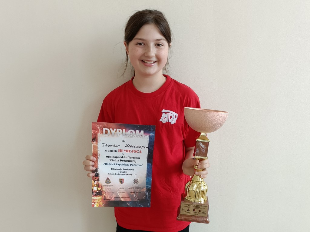 Uczennica prezentuje dyplom i puchar za zdobycie trzeciego miejsca w konkursie
