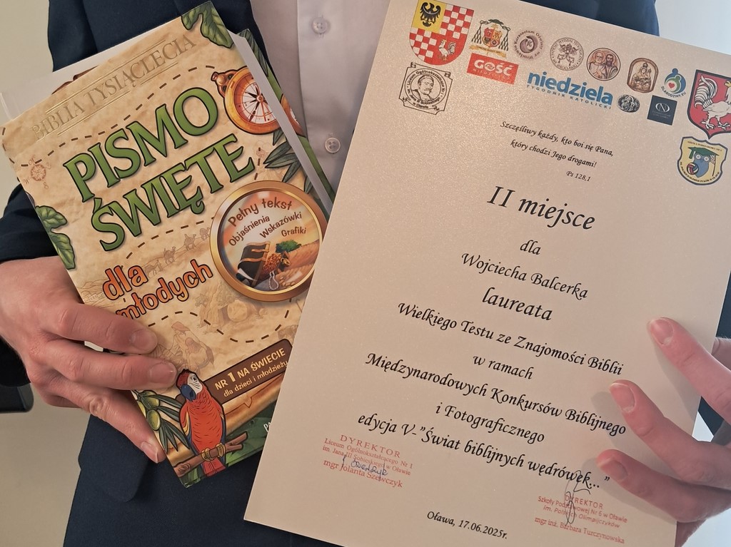 Uczeń prezentuje dyplom i nagrodę uzyskane w konkursie